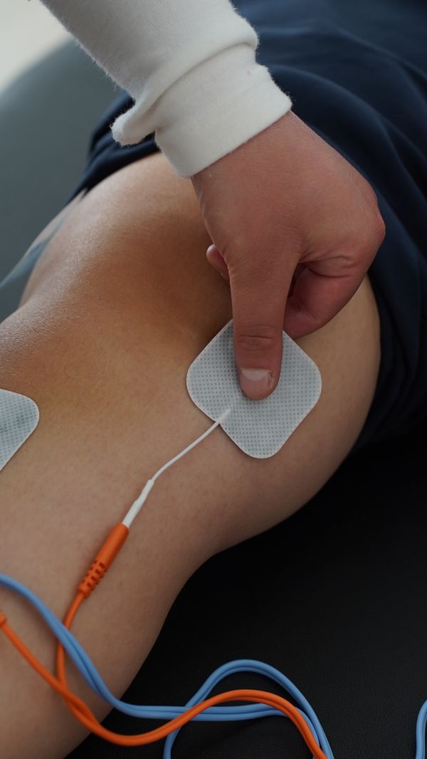Profesional coloca electrodos de electroestimulación sobre la rodilla de un paciente.