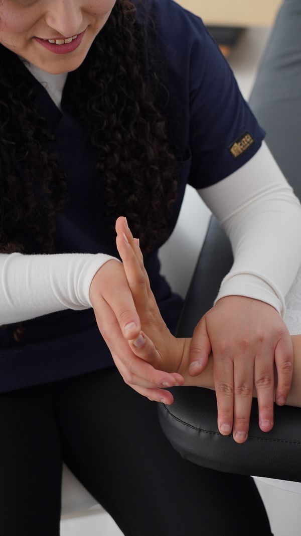Terapeuta moviliza la muñeca y los dedos de una paciente durante una sesión de terapia de mano.